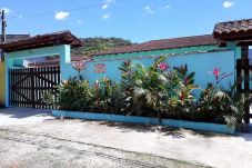 Fachada da casa em Ubatuba, com muro azul, jardins e portões de madeira